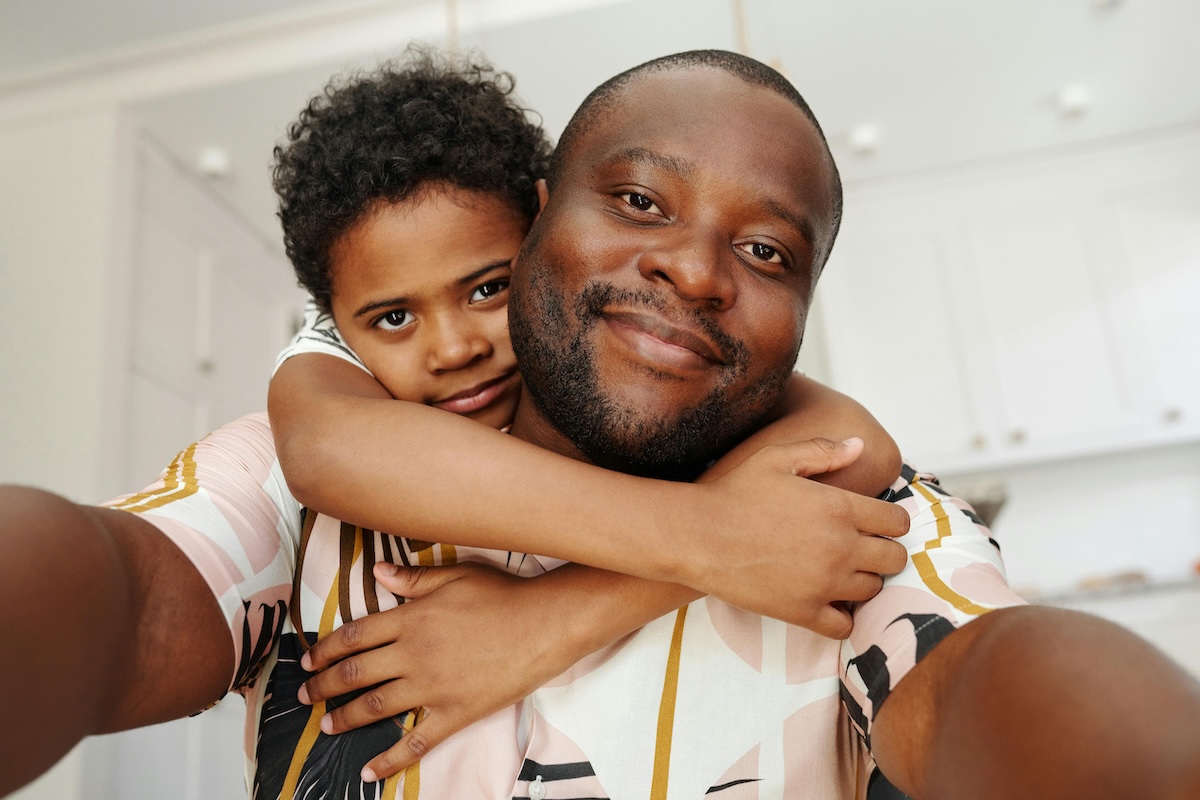 selfie of young boy hugging dad from behind